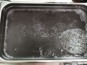 Close-up of an ultrasonic cleaner tank filled with murky solution